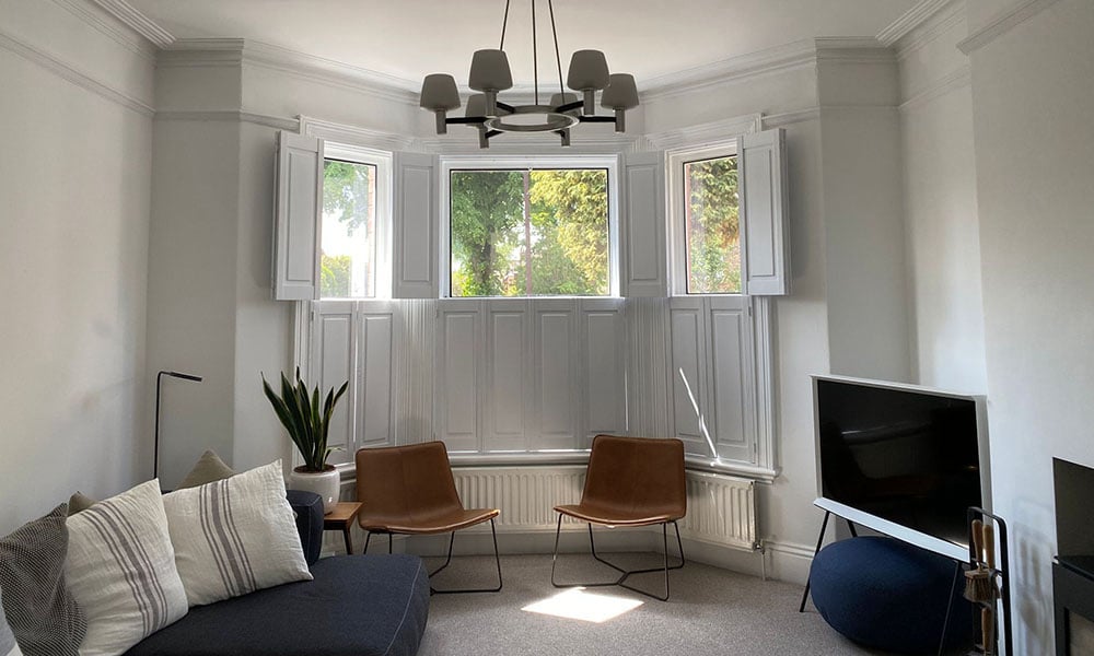 Plné panelové okenice na mieru v obývačke s arkierovým oknom